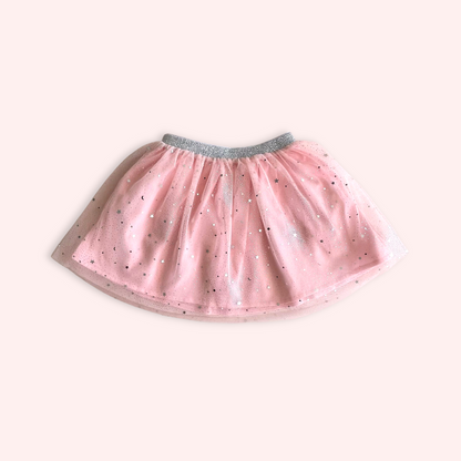 Falda de tutú rosa para niña sobre fondo de madera azul.